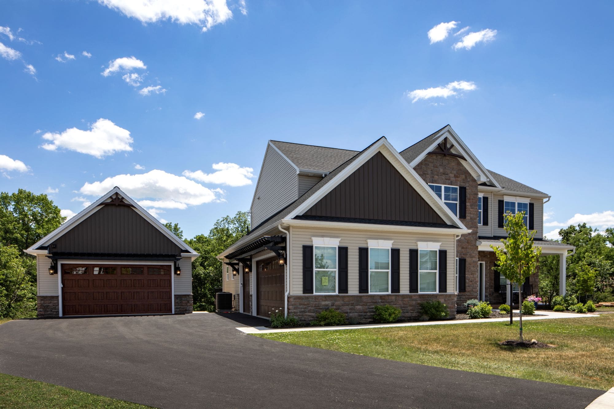 Two-story suburban house with a detached garage, brown and white exterior, gabled roof, and a paved driveway. This is a garage addition built by McNaughton Homes.